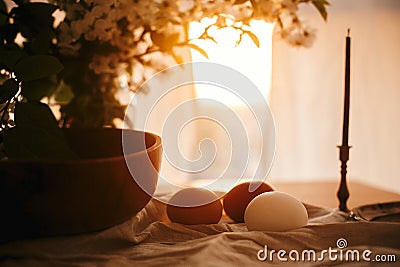 Rural Easter still life. Natural eggs and vintage candle on linen fabric on background of rustic table with cherry flowers and Stock Photo