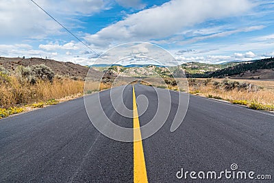 Rural highway disappearing into distance surrounded by grasslands in autumn Stock Photo