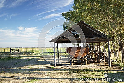 Rural landscape: barn car under an old shed, pasture, gate and blue sky clouds Stock Photo
