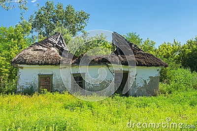 Rural landscape with classic ruined and abandoned clay walled house under straw roof Stock Photo