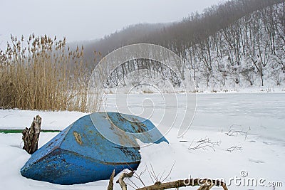 Rural landscape of frozen river and fishing bottom up boat Stock Photo