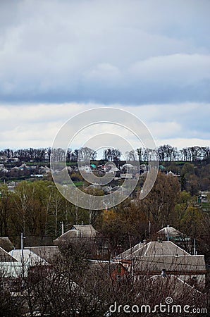 A rural landscape with many private houses and green trees. Suburban panorama on a cloudy afternoon. A place far from the cit Stock Photo