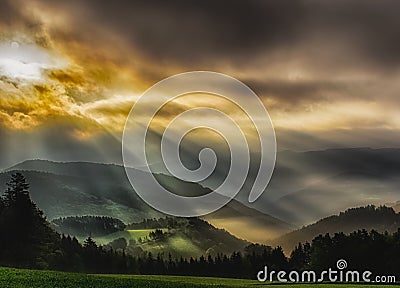 Foggy epic glorious sunrise over a countryside with hills,fields, trees,dramatic sky Stock Photo