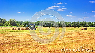 Rural landscape - tractor harvesting large round bales of straw in the field after harvest Editorial Stock Photo