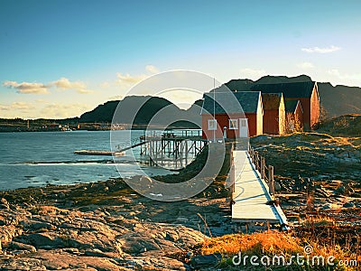 Rural Norwegian landscape, traditional red and white wooden house on rocky island. Suny spring day with smooth water Stock Photo