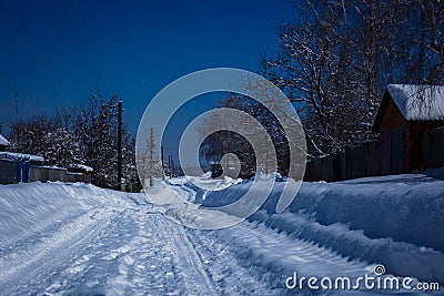 Rural road in snowdrift lit by moonlight at night Stock Photo