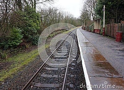 Rural single railway track and train station on a rainy day Stock Photo