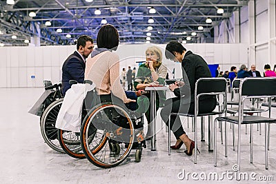 Russia, city Moscow - December 18, 2017: Young woman in a wheelchair. A group of people discussing a project at a Editorial Stock Photo