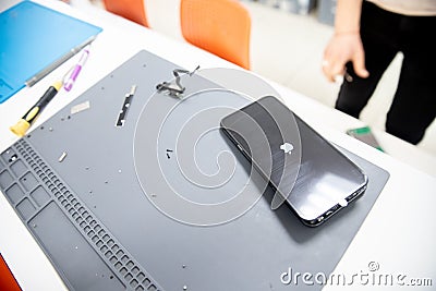 RUSSIA - July 27, 2020: Repair iPhone apple broken phone screen and replace used rechargeable batteries for recycling Editorial Stock Photo