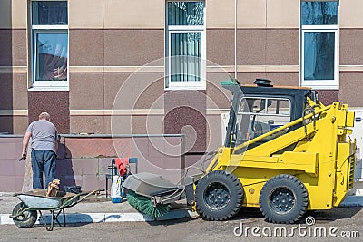 Russia, Kazan - April 12, 2019: An elderly man lays tiles on a wall outside. Editorial Stock Photo