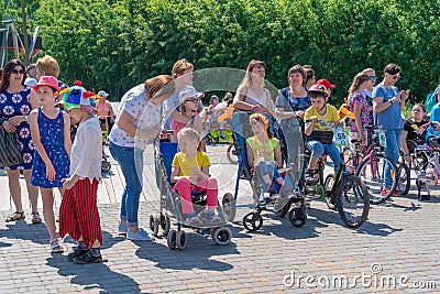 Russia, Kazan - May 31, 2019: Disabled boy with glasses on a four-wheeled bicycle on a bright sunny day. Girls in wheelchairs Editorial Stock Photo