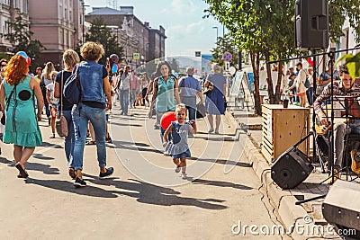 RUSSIA, Krasnoyarsk - August 25: A little girl with a red balloon runs among people along Prospekt Mira on the day of the 390th Editorial Stock Photo
