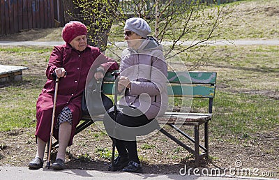 Women of retirement age sit on a bench and discuss the news Editorial Stock Photo