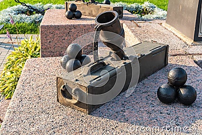 Russia, Kronstadt, September 2020. An old portable cannon with cannonballs at the foot of the monument. Editorial Stock Photo