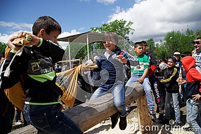 Russia, Magnitogorsk, - June, 15, 2019. Children are recklessly fighting with bags on a log during the holiday Sabantuy. National Editorial Stock Photo