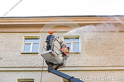 22.05.2019 Russia, Moscow. The employee of municipal services washes a facade of the multi-storey building by means of the high- Editorial Stock Photo