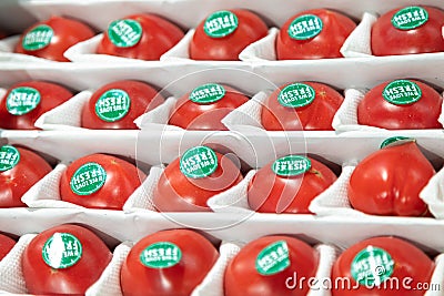 24.04.2021, Russia, Moscow. Large juicy varietal tomatoes with green labels on the side lie in a box Editorial Stock Photo