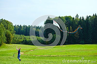 Russia, Moscow, 02.06.2019, man launches a kite in a huge green field, next to a dense forest Editorial Stock Photo