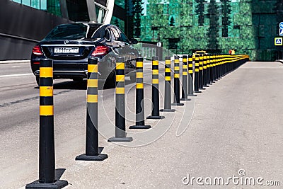 Russia Moscow 2019-06-17 parking limiter black round pillows with yellow stripes between roadway and sidewalk on background car Editorial Stock Photo