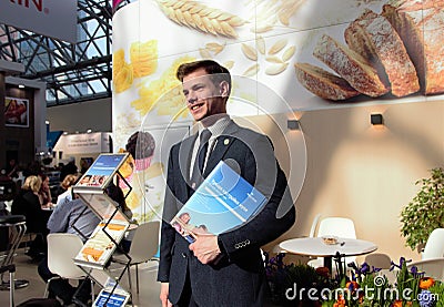 03.14.2019 Russia, Moscow. smiling man, in a business suit, stands against the background of an information stand with Editorial Stock Photo