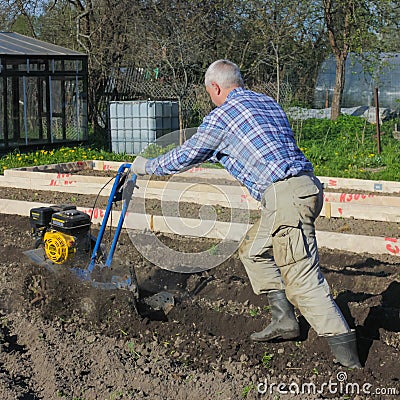 05/25/2012. Russia. Nikolsky. The farmer plows the ground with a motor-block. Plowing the grou Editorial Stock Photo