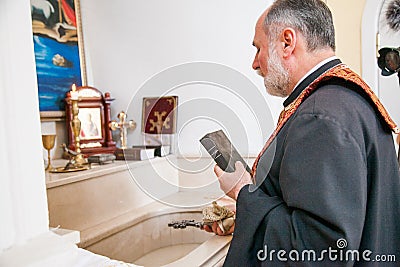 Russia, Rostov-on-Don - May 30, 2014: An Armenian priest with a cross and a bible performs the rite of baptism over the font Editorial Stock Photo