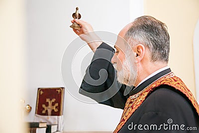 Russia, Rostov-on-Don - May 30, 2014: An Armenian priest holds a bird figurine in his hand and performs the rite of baptism over Editorial Stock Photo