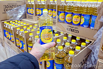 A man`s hand holds a bottle of sunflower oil and chooses in a store. Editorial Stock Photo