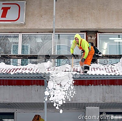 A communal service worker cleans the roof of the house of accumulated snow Editorial Stock Photo