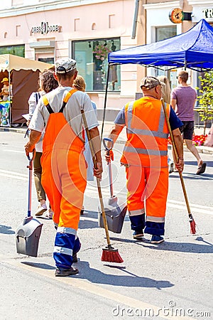 Community workers are walking along the street with a tool in their hands at work Editorial Stock Photo