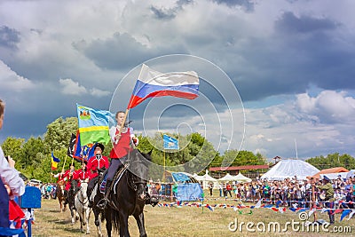 Solemn entry of a group of horse racing with flags in the meadow of the festival Editorial Stock Photo