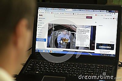 A young man browses the home page of the official website of AOL, a web portal and online service provider, on a laptop at night Editorial Stock Photo