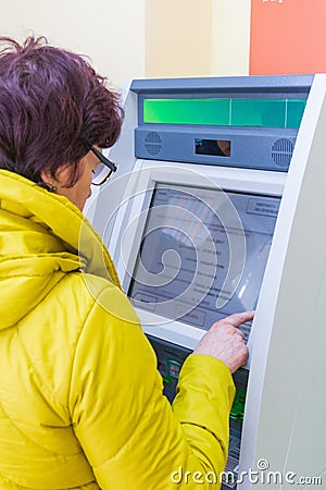 Samara, November 2018: Mature beautiful woman pays utilities through an ATM Editorial Stock Photo