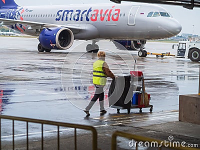 Russia, Sochi 02.11.2021. A cleaning lady in a yellow vest with a cart and equipment walks along the airfield past the Editorial Stock Photo