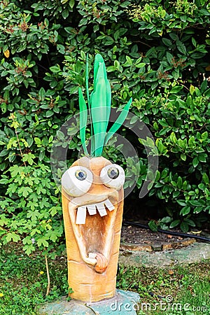 Russia, Sochi 14.05.2022. Crazy big-eyed carrot screams with his tongue out. Cartoon garden figurine on the lawn Editorial Stock Photo