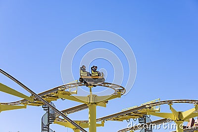 Russia, Sochi 14.05.2022. People in a yellow open trailer ride on an attraction against a blue sky. Extreme attraction Editorial Stock Photo