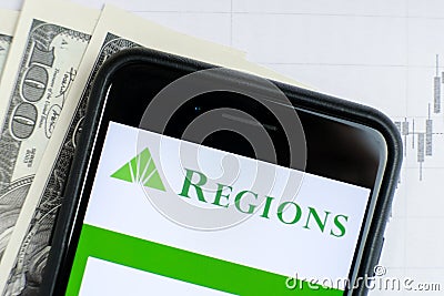 RUSSIA, ST.PETERSBURG, April 4, 2019: Logo Regions Financial Corporation in the smartphone lying charts and dollar Editorial Stock Photo