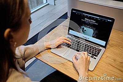 RUSSIA, ST.PETERSBURG - March 5: A girl browses an Apple site on a macbook. Looking for an iPhone Editorial Stock Photo