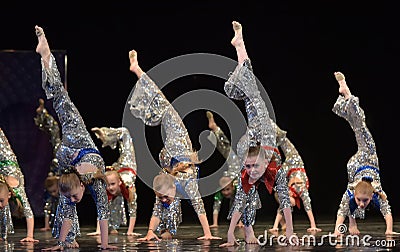 Performance of a children`s dance group in shiny costumes, in the style of disco at the open festival of creativity Editorial Stock Photo