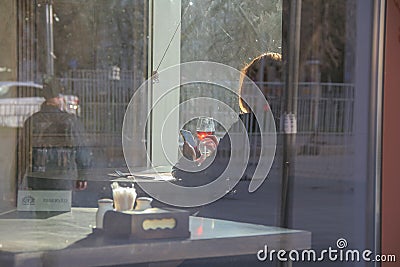 Russia, St. Petersburg, the silhouette of a girl in a cafe with a glass of red wine. Summer bright light, the sun`s rays permeate Stock Photo