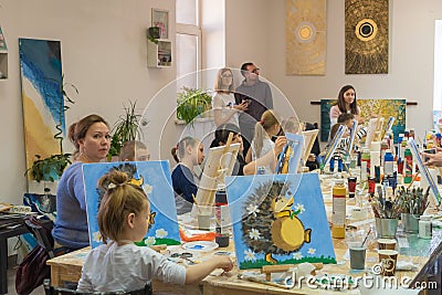 Russia, Tatarstan, April 21, 2019. Children`s drawing class. Easel, canvases, paints on the table. A group of children draw Editorial Stock Photo