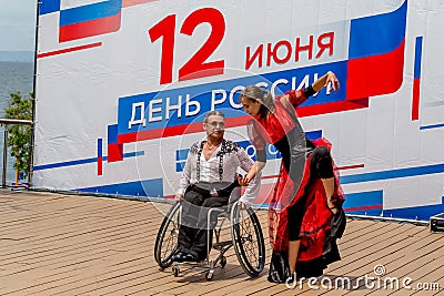 Russia, Vladivostok, 06/12/2018. Actor in wheelchair and usual actor perform the dance on stage. Annual celebration Russia Day on Editorial Stock Photo
