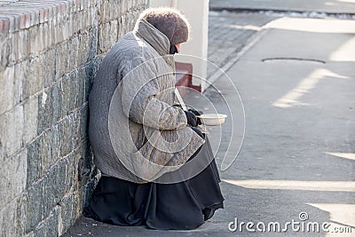 Elderly poor woman begging alms in the street in a cold winter day Editorial Stock Photo