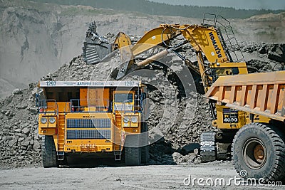 Komatsu PC4000 electric excavator loads ore mass into BelAZ dump truck. The action takes Editorial Stock Photo