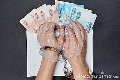 Russian banknotes in an envelope on the table. The concept of a bribe. Women& x27;s hands in handcuffs. Gray salary Stock Photo