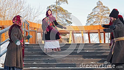 Russian folklore at ours time - young people in felt boots are dancing on the stairs in the winter park Stock Photo