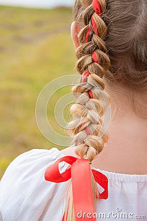 Russian girl Slavic appearance with braids with red ribbons in the field in autumn Stock Photo