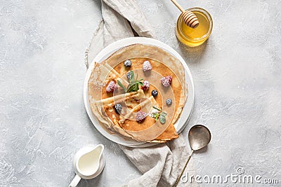 Russian pancakes or blini with honey, berries and milk on light background. Springtime. Shrovetide. View from above Stock Photo