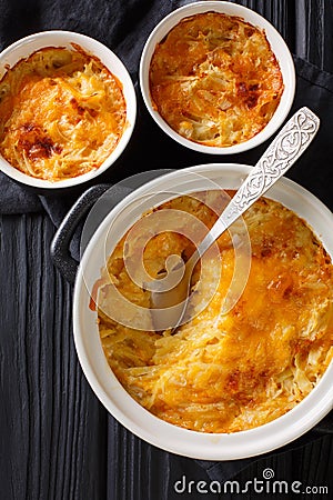Russian Romanoff casserole made from potatoes, sour cream and cheddar cheese close-up in a pan. Vertical top view Stock Photo