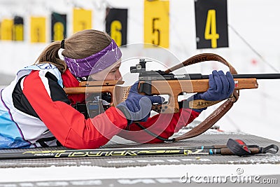 Russian sportswoman biathlete Vakhrusheva Valentina rifle shooting in prone position. Biathlete in shooting range. Junior biathlon Editorial Stock Photo